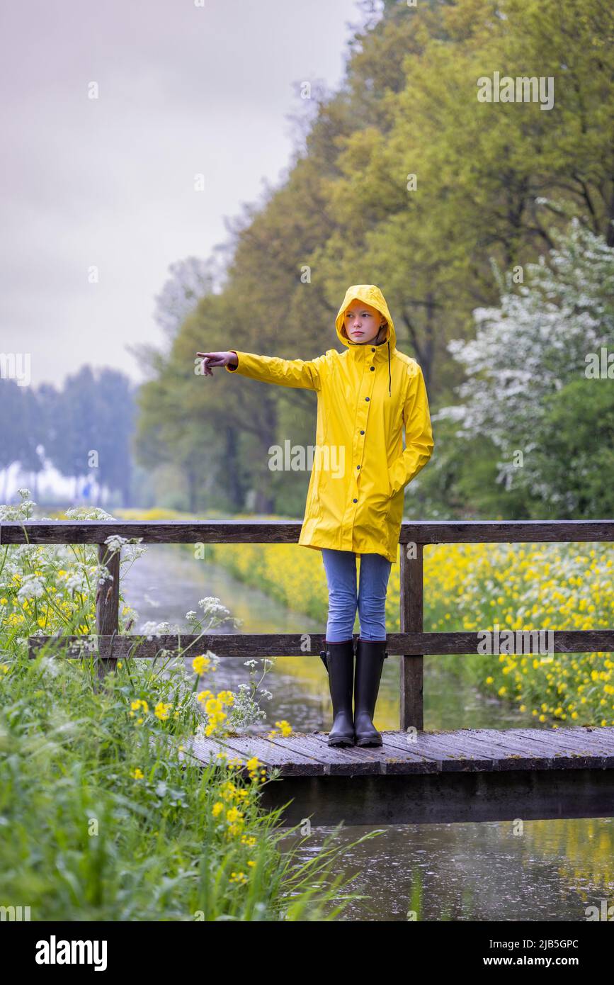 Mujer joven con chubasquero amarillo y botas de goma en la naturaleza  primaveral Fotografía de stock - Alamy