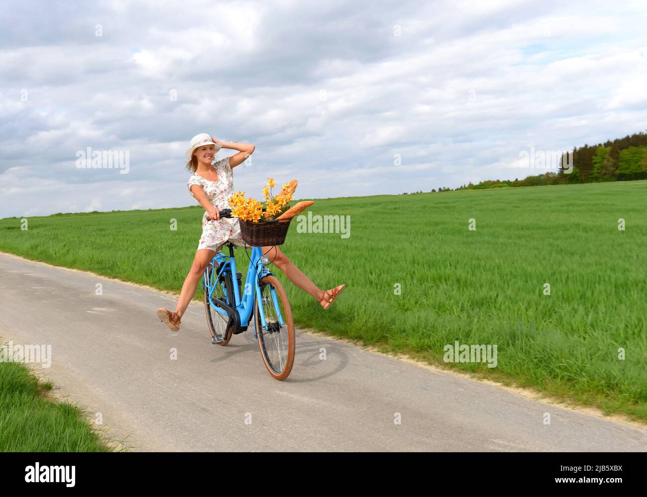 Una joven sin preocupaciones disfruta de su nueva bicicleta híbrida eléctrica. Ella se lleva para un paseo relajante en el país sin usar sus pedales de bicicleta. Foto de stock