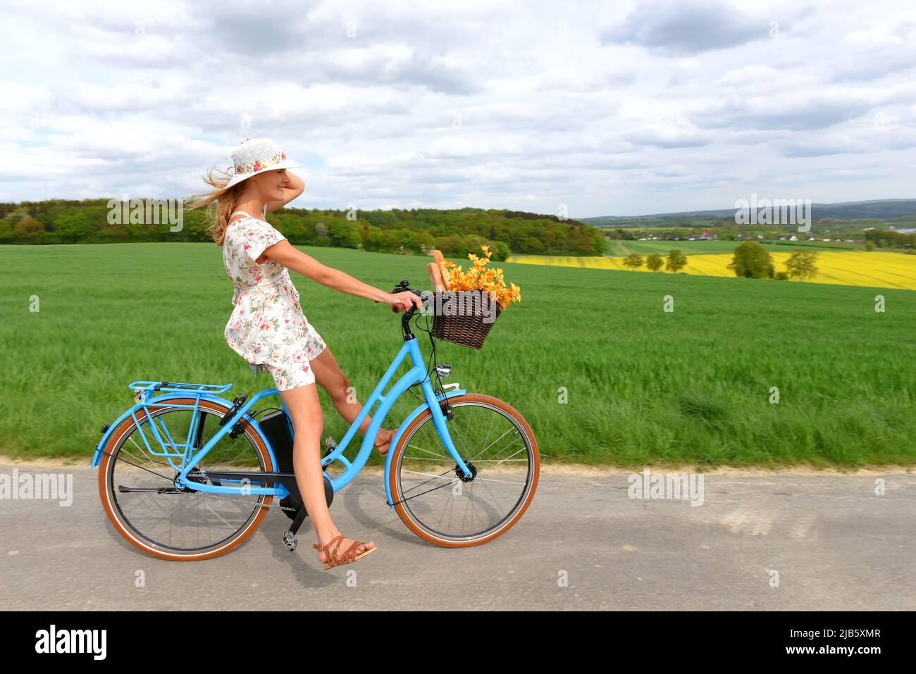 Una joven sin preocupaciones disfruta de su nueva bicicleta híbrida eléctrica. Ella se lleva para un paseo relajante en el país sin usar sus pedales de bicicleta. Foto de stock