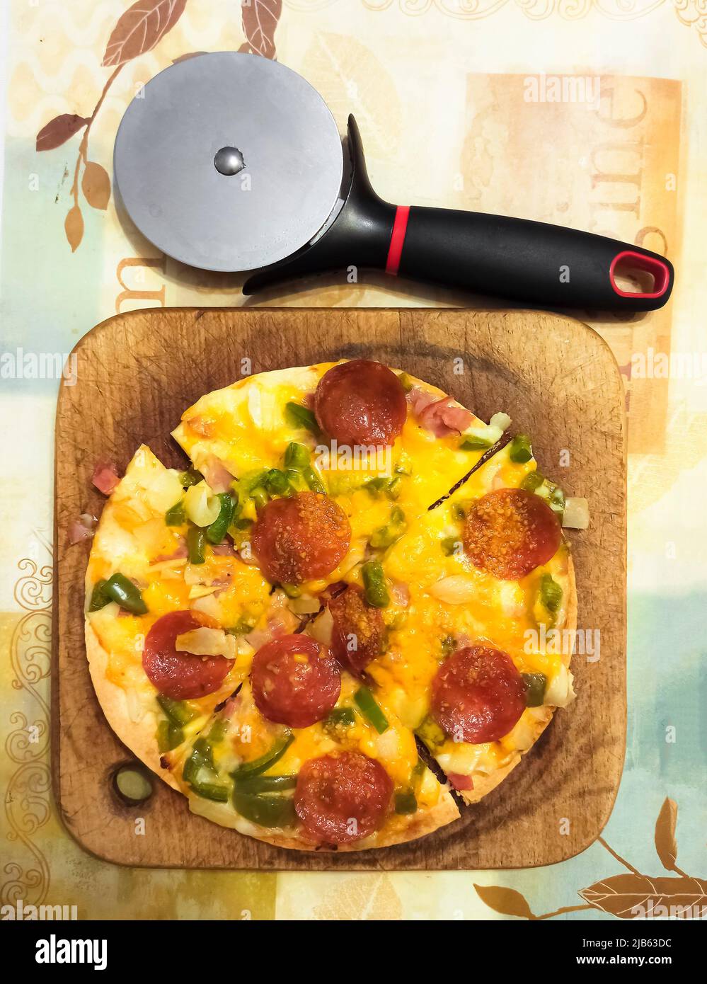 Pizza casera de crujiente fina. Ingredientes: Pimiento verde, cebollas, pepperoni; queso mozzarela, queso parmesano; queso cheddar afilado. Foto de stock