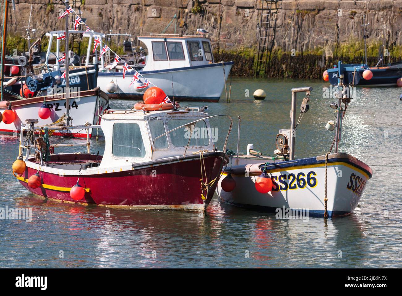Barcos de pesca y otras pequeñas embarcaciones en el puerto pesquero de Cornualles de Porthleven. En primer plano se muestran de langosta amarrados de color rojo y blanco Fotografía de stock -