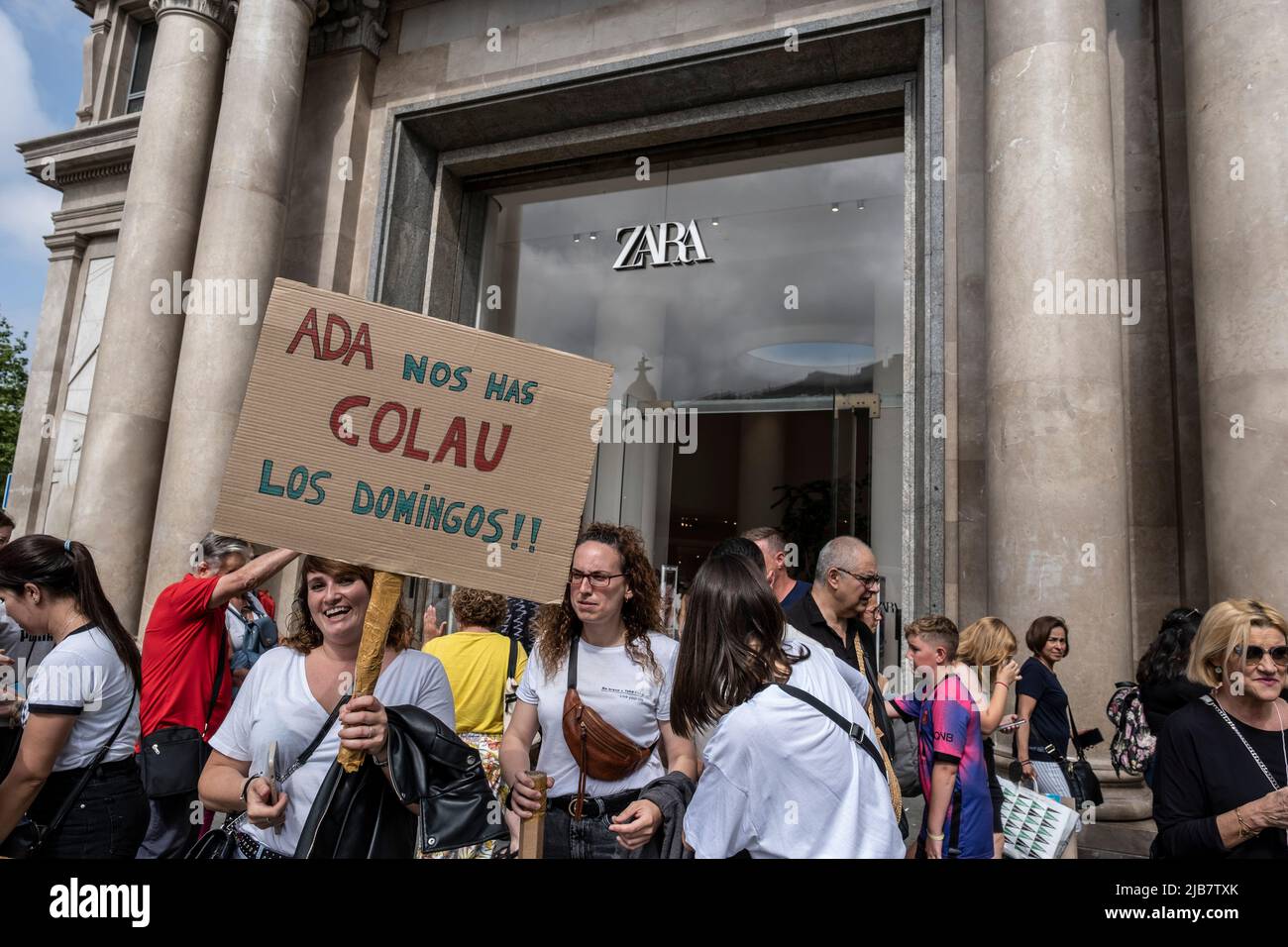 Un manifestante es visto frente a la puerta de Zara sosteniendo un cartel  acusando al Alcalde Ada Colau de haber ratificado el nuevo horario de  trabajo para los domingos durante la manifestación.