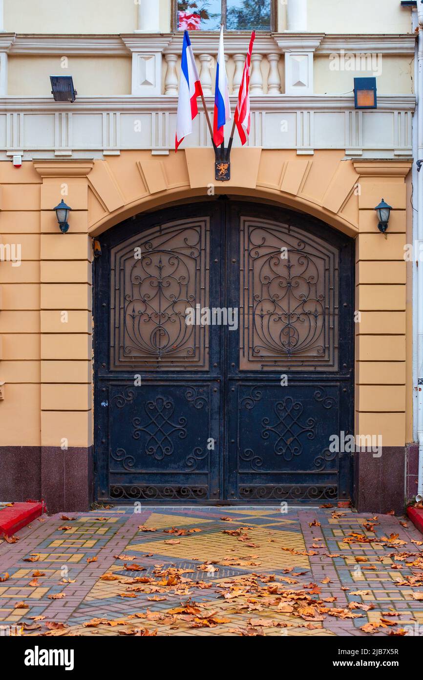 Tres banderas de Rusia, Crimea y Kerch sobre la puerta con barras de hierro  en un día de otoño. Kerch, Crimea-04.11.2021 Fotografía de stock - Alamy