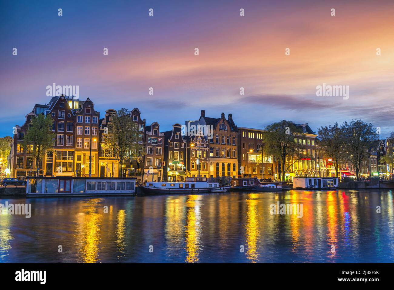 Amsterdam, Países Bajos, atardecer, el horizonte de la ciudad de casa holandesa en canal waterfront Foto de stock