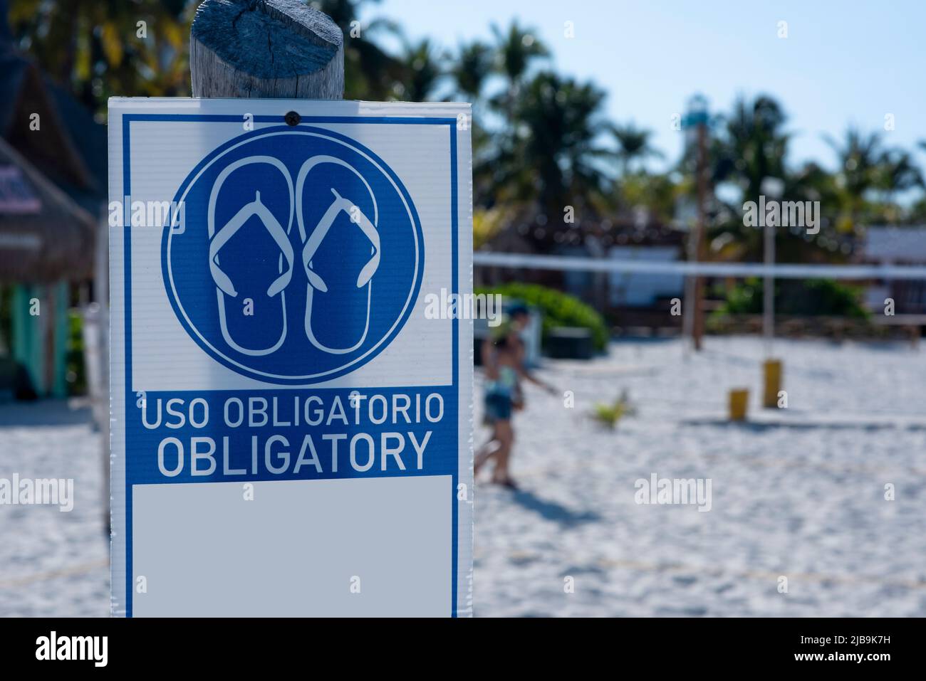 Firme en español e inglés en la playa como 'obligatorio'. Es obligatorio  usar chanclas en la playa Fotografía de stock - Alamy