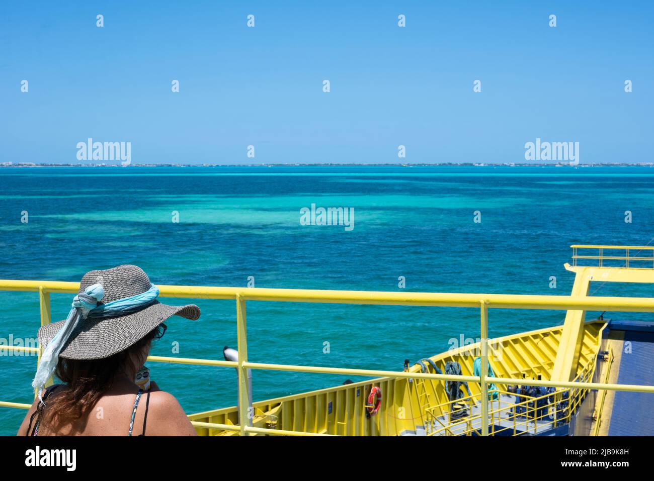 Vista trasera de una mujer en un sombrero sentado en la cubierta de un ferry en México Foto de stock