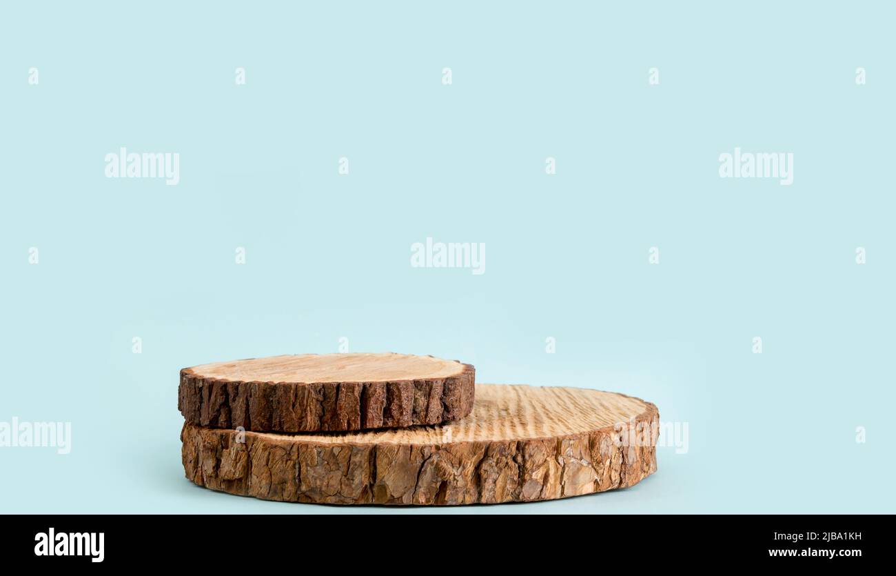 Dos discos de madera de pino apilados como un podio para productos, fondo de color azul con mucho espacio de copia, estudio grabado. Foto de stock