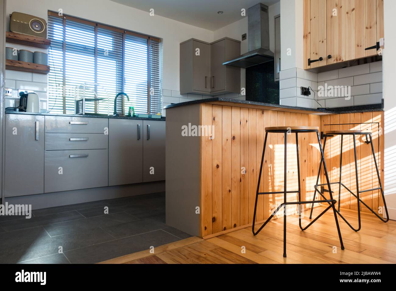 Vista a un nivel bajo de una cocina moderna con taburete alto de desayuno y otros equipos básicos Foto de stock