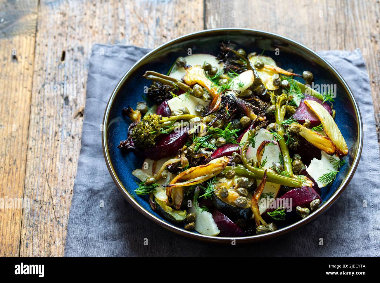 Ensalada caliente con escarabajos asados, brócoli, manzana, hinojo y alcaparras crujientes Foto de stock