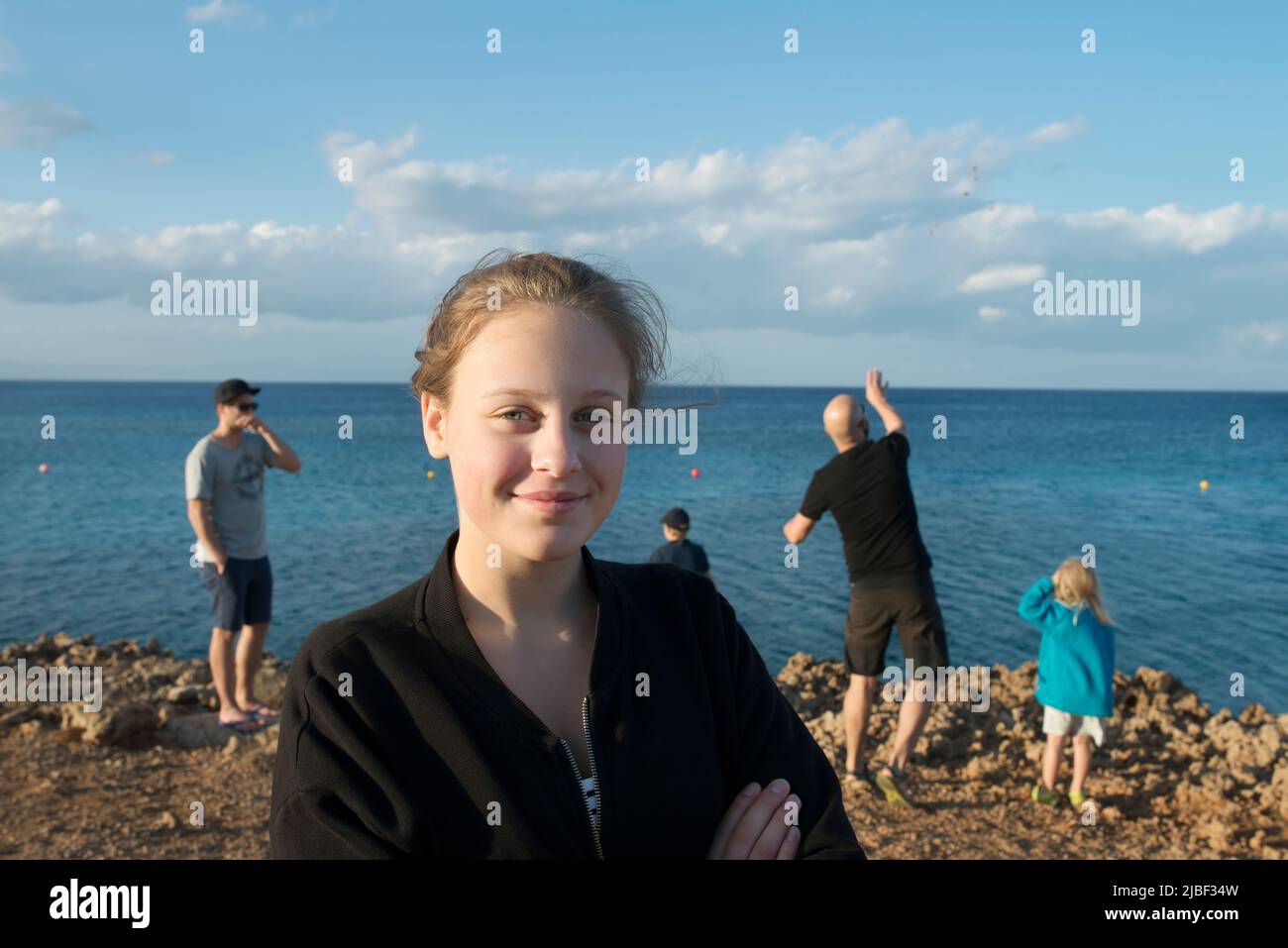 Chica sonriente con su familia por mar Foto de stock