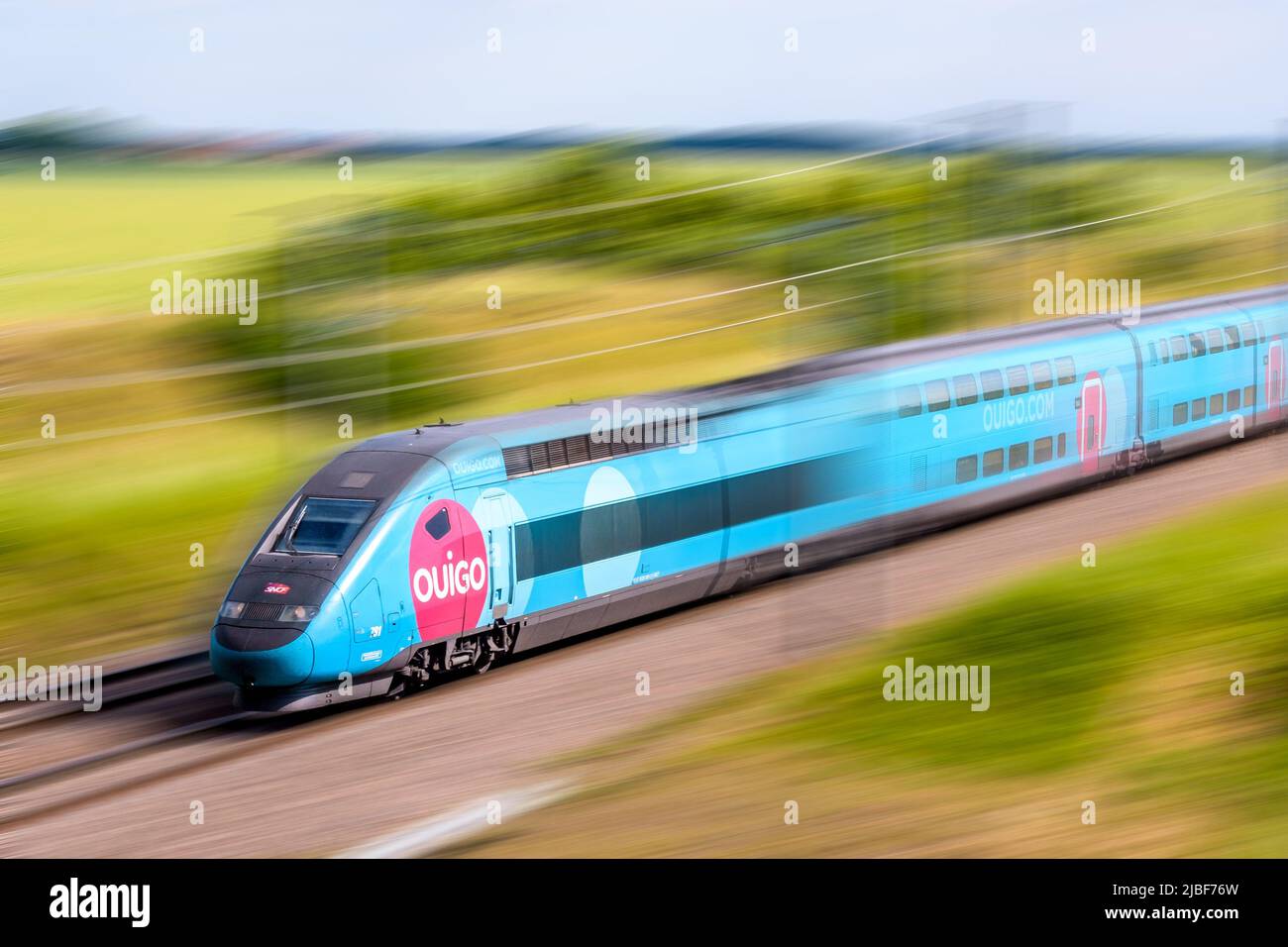 Un tren TGV Duplex Ouigo de alta velocidad de la compañía francesa de trenes SNCF está conduciendo a toda velocidad en el campo. Foto de stock