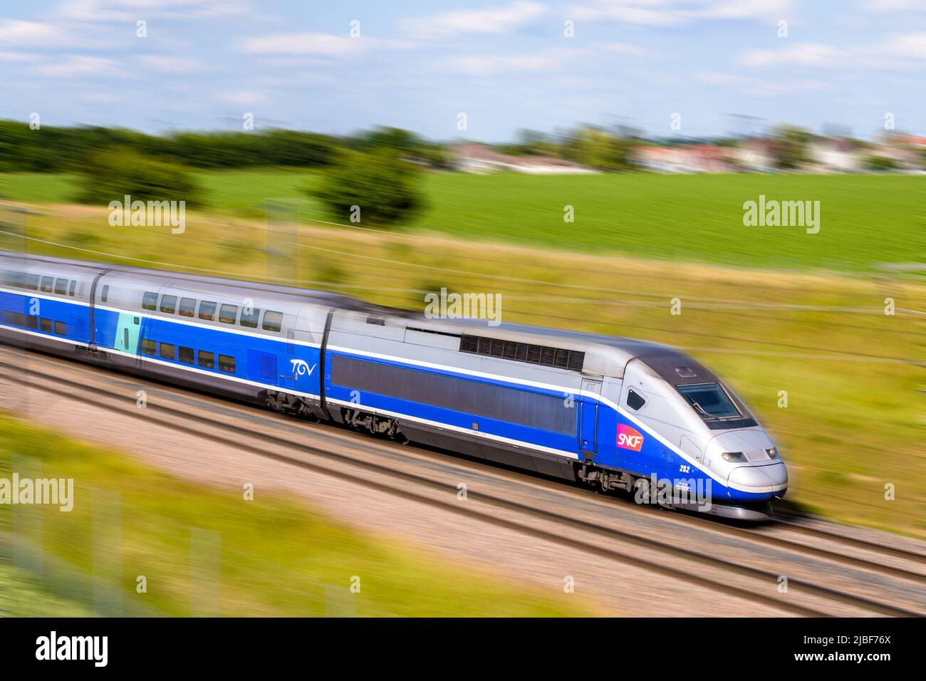 Un tren TGV Duplex de alta velocidad de la compañía francesa de trenes SNCF está conduciendo a toda velocidad en el campo. Foto de stock