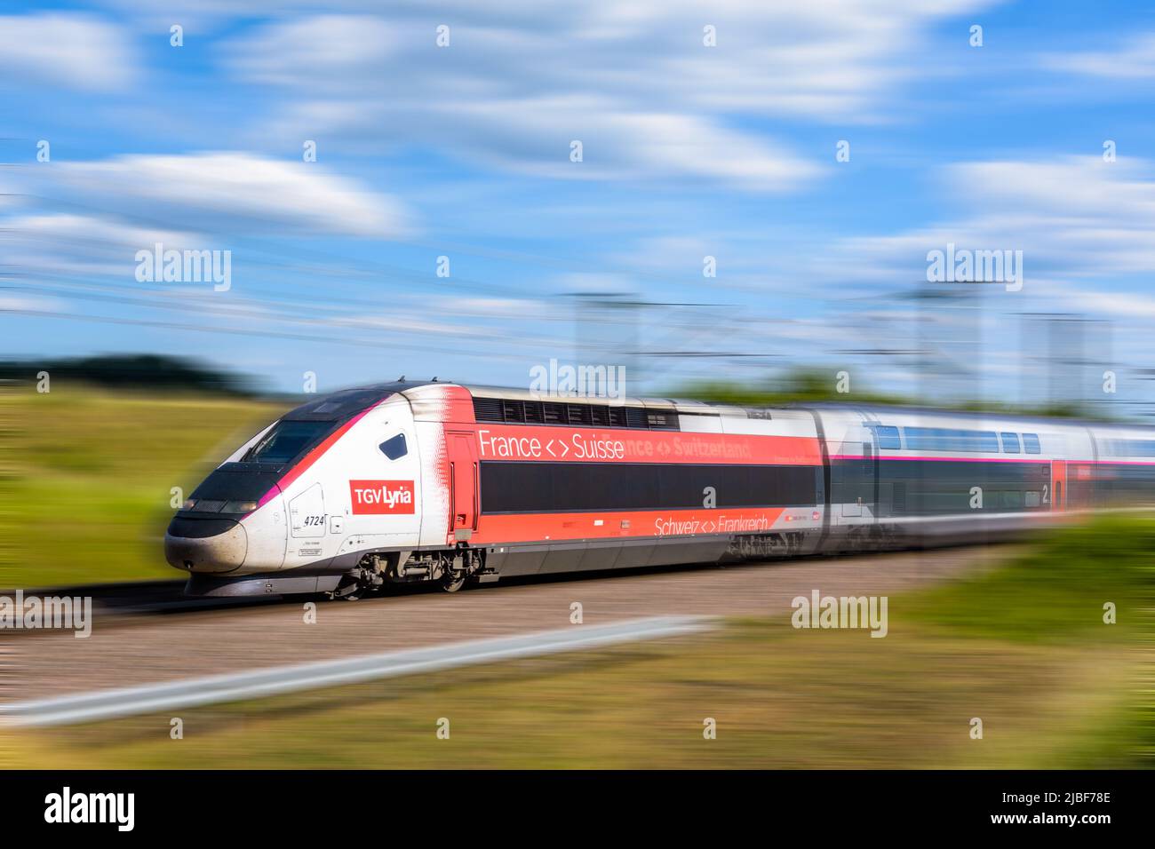 Un tren de alta velocidad TGV Euroduplex de la compañía ferroviaria franco-suiza Lyria está conduciendo a toda velocidad en el campo. Foto de stock