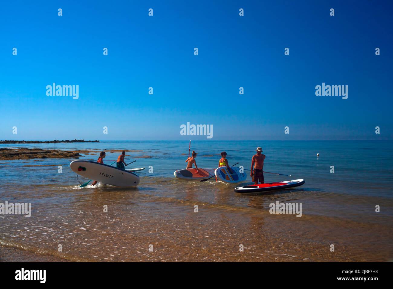 Realmonte, Italia - 23 de julio,: Stand up paddle boarding. Alegre grupo de amigos entrenando SUP board en el mar mediterráneo en una mañana soleada en Re Foto de stock