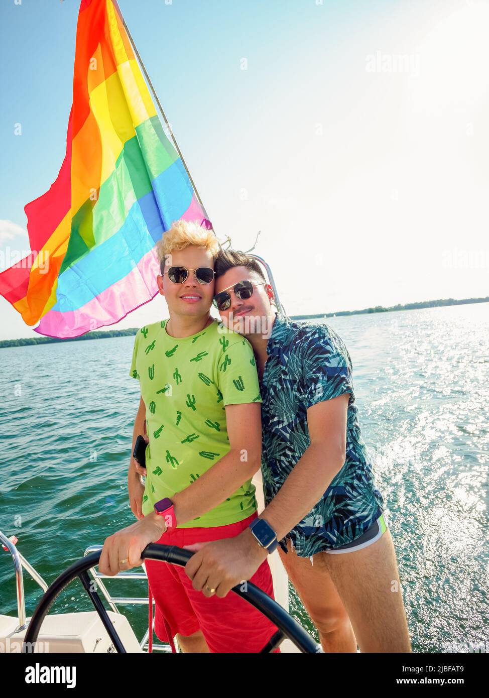 volante juntos, la pareja gay tiene unas vacaciones en un yate de vela con  la bandera del arco iris lgbt Fotografía de stock - Alamy