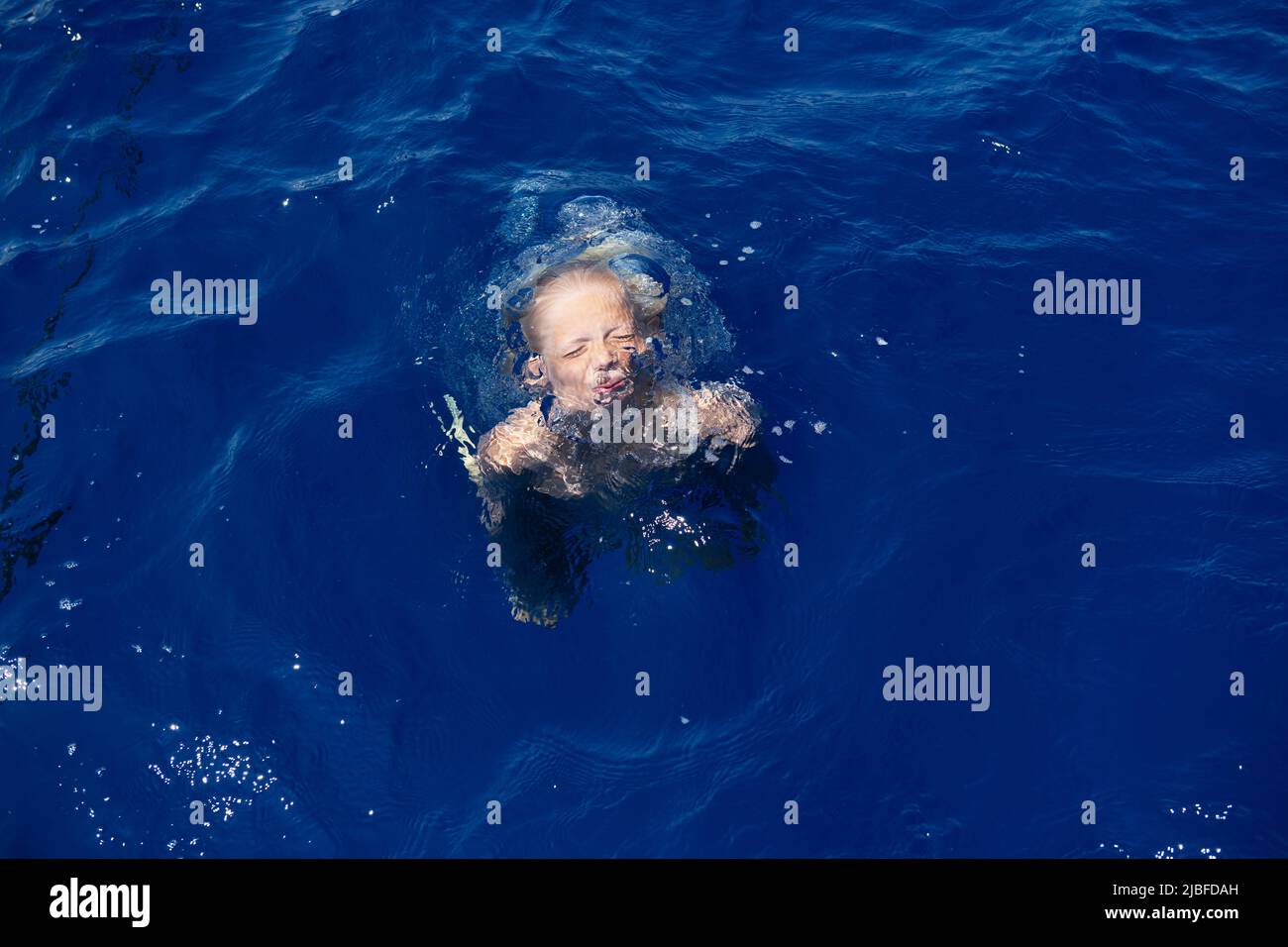 Chico con sus ojos cerrados bajo el agua en el mar Foto de stock