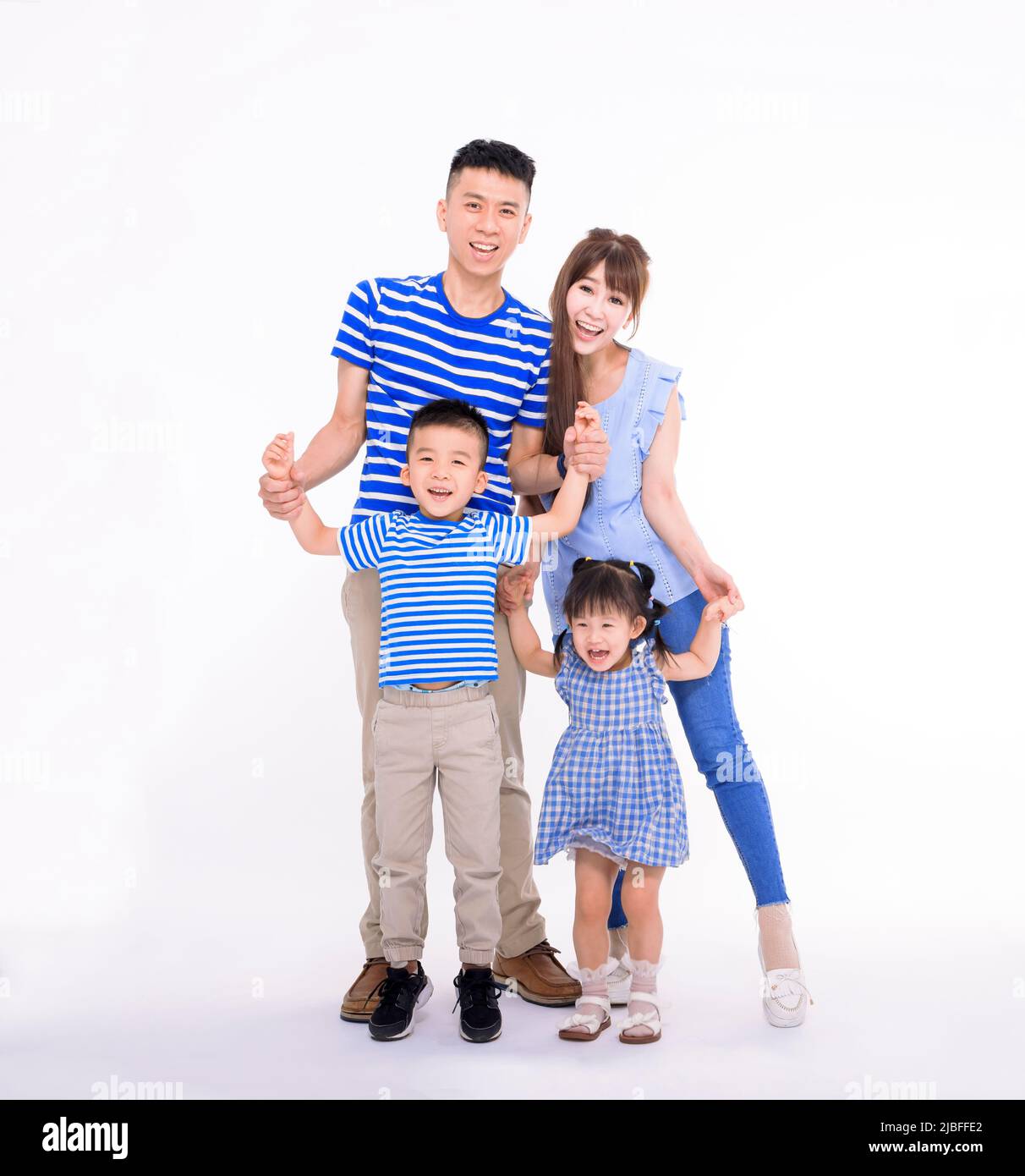 Feliz familia asiática joven con niños de pie abrazando y sonriendo en la cámara aislada sobre fondo blanco Foto de stock