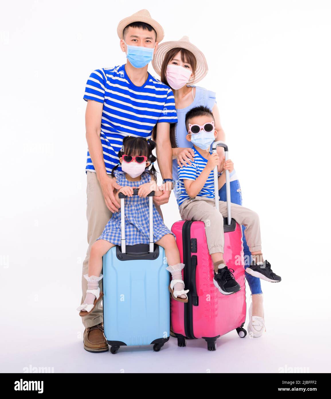 Familia feliz en máscaras que sostienen las maletas aisladas sobre fondo blanco. Gente preparada para vacaciones de verano, concepto de viaje seguro Foto de stock
