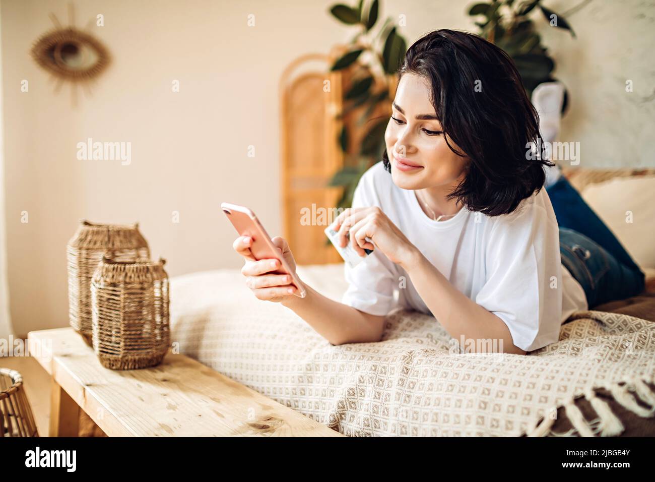 Sonriente niña compra en línea utilizando el teléfono Foto de stock