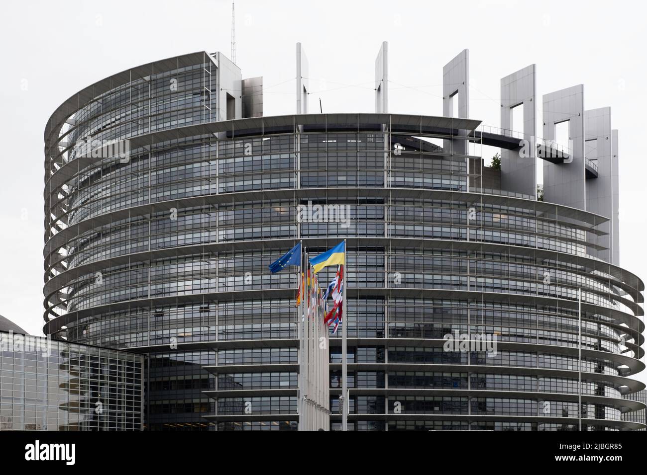 Fachada circular del edificio Louise Weiss del Parlamento Europeo con banderas de los 27 países, incluida la de Ucrania, en Estrasburgo Foto de stock