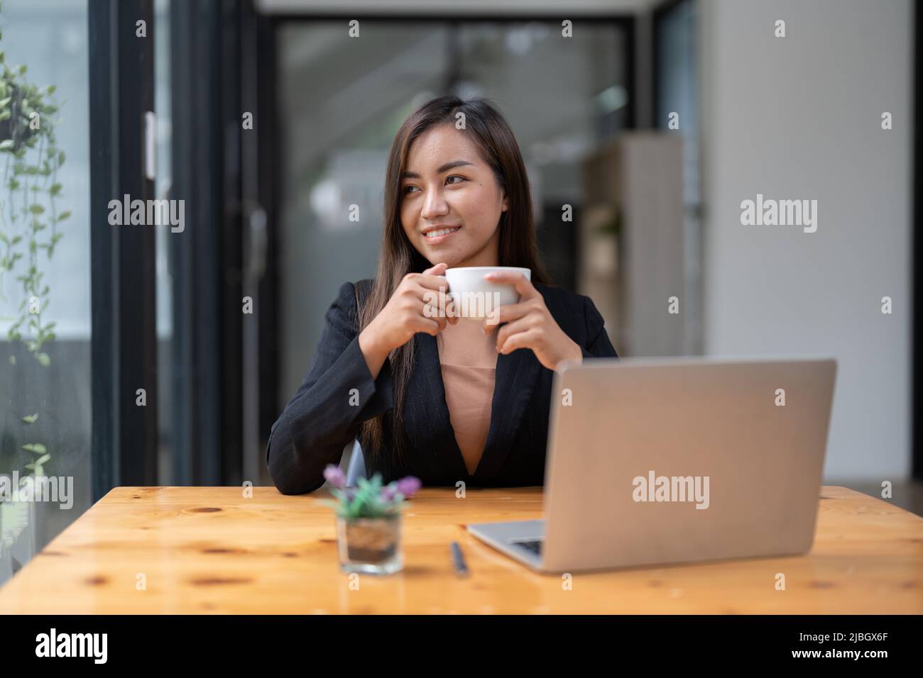 Retrato de la joven mujer asiática independiente en línea que trabaja desde casa con ordenador portátil. Foto de stock