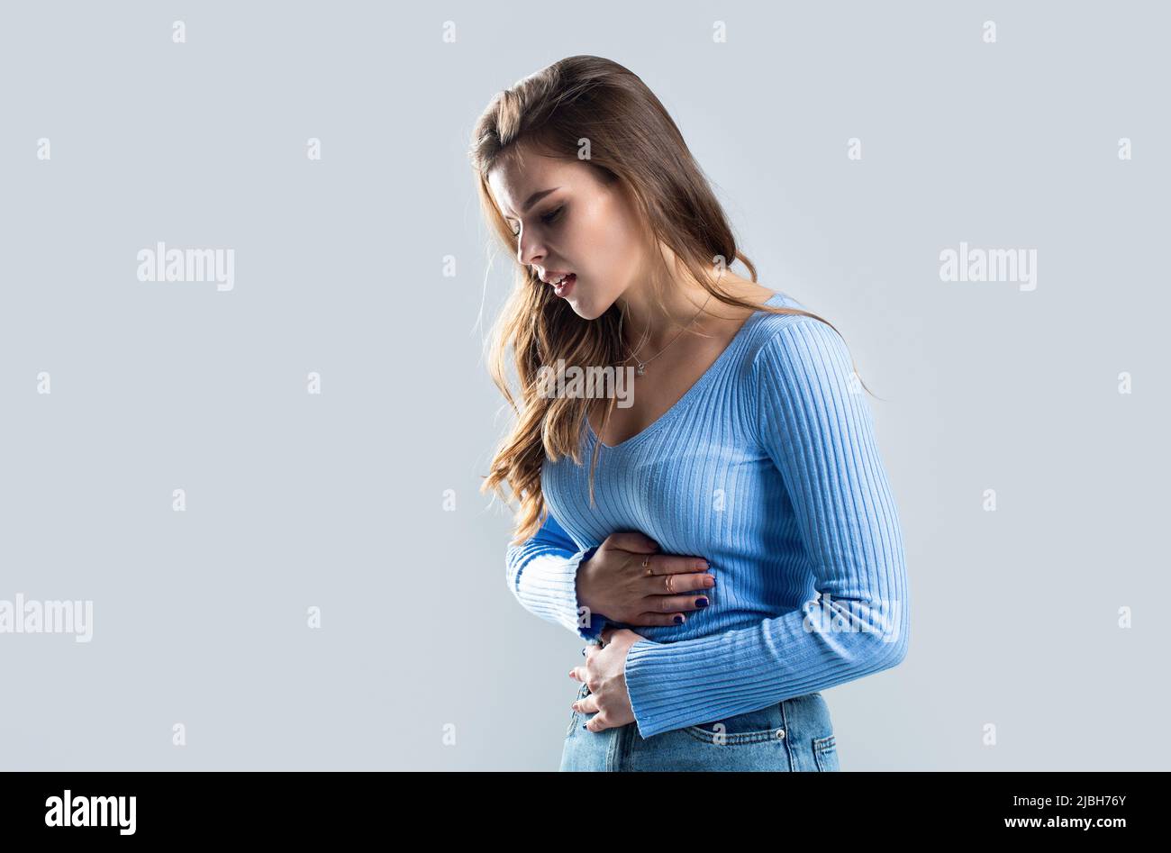 Mujer tocando su estómago. Concepto de dolor de estómago y otras enfermedades estomacales.Chica con dolor de estómago. Mujer joven que sufre de dolor abdominal Foto de stock