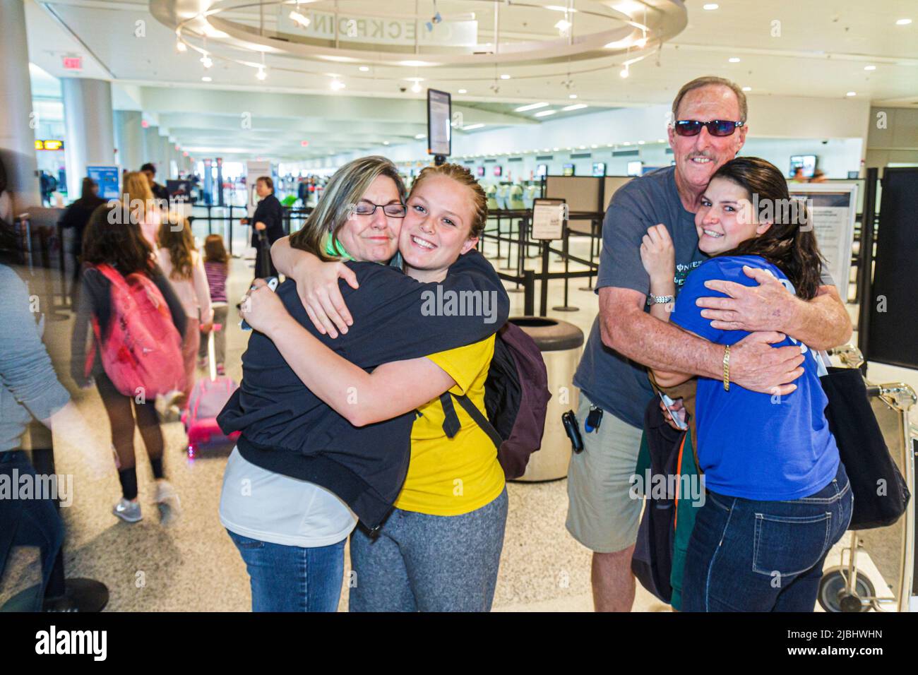 Aeropuerto Internacional Miami Florida MIA, terminal dentro del interior, padre madre padres hija abrazando diciendo Adiós viajar saliendo Foto de stock