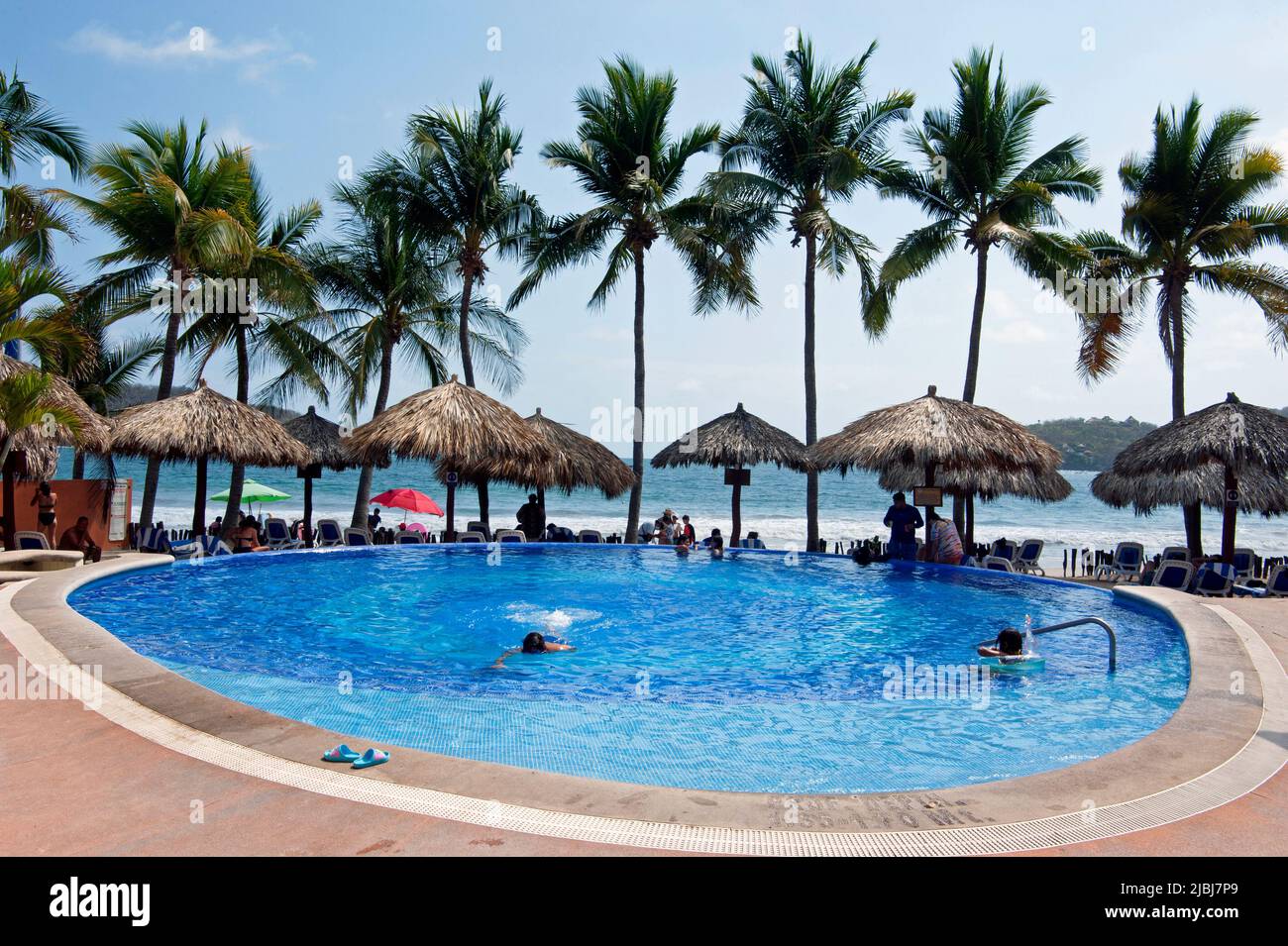 Hotel frente a la playa con piscina y palmeras en Zihuatanejo, México Foto de stock