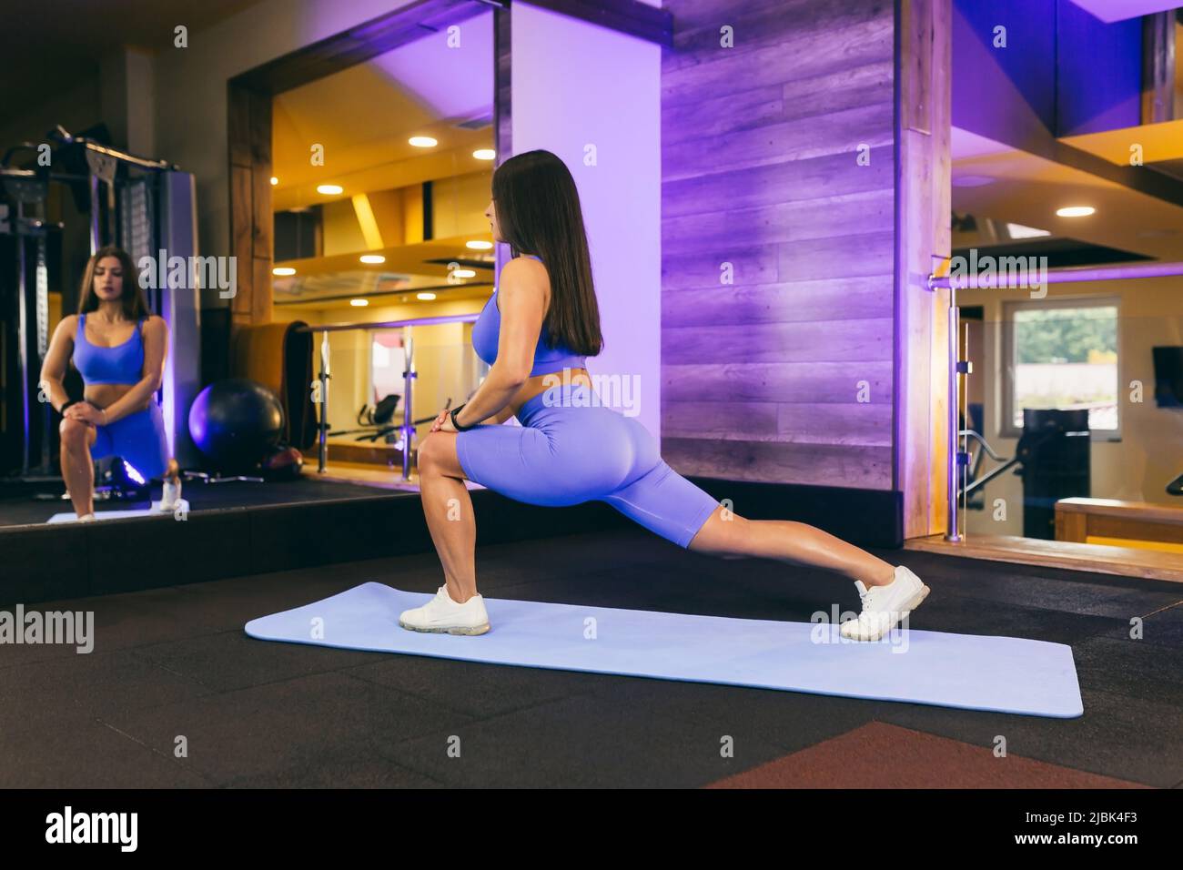 Una chica en el gimnasio hace yoga y fitness en una colchoneta de gimnasia