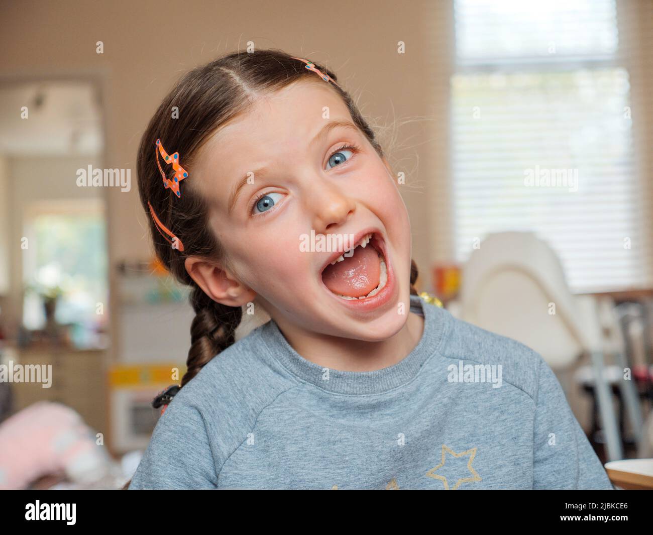 Retrato de una chica feliz sonriente de siete años que ha perdido sus dientes delanteros del bebé que se han caído Foto de stock