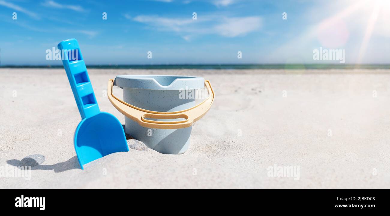 vista de cerca del balde de juguete y de la playa de arena contra el mar y el cielo azul Foto de stock