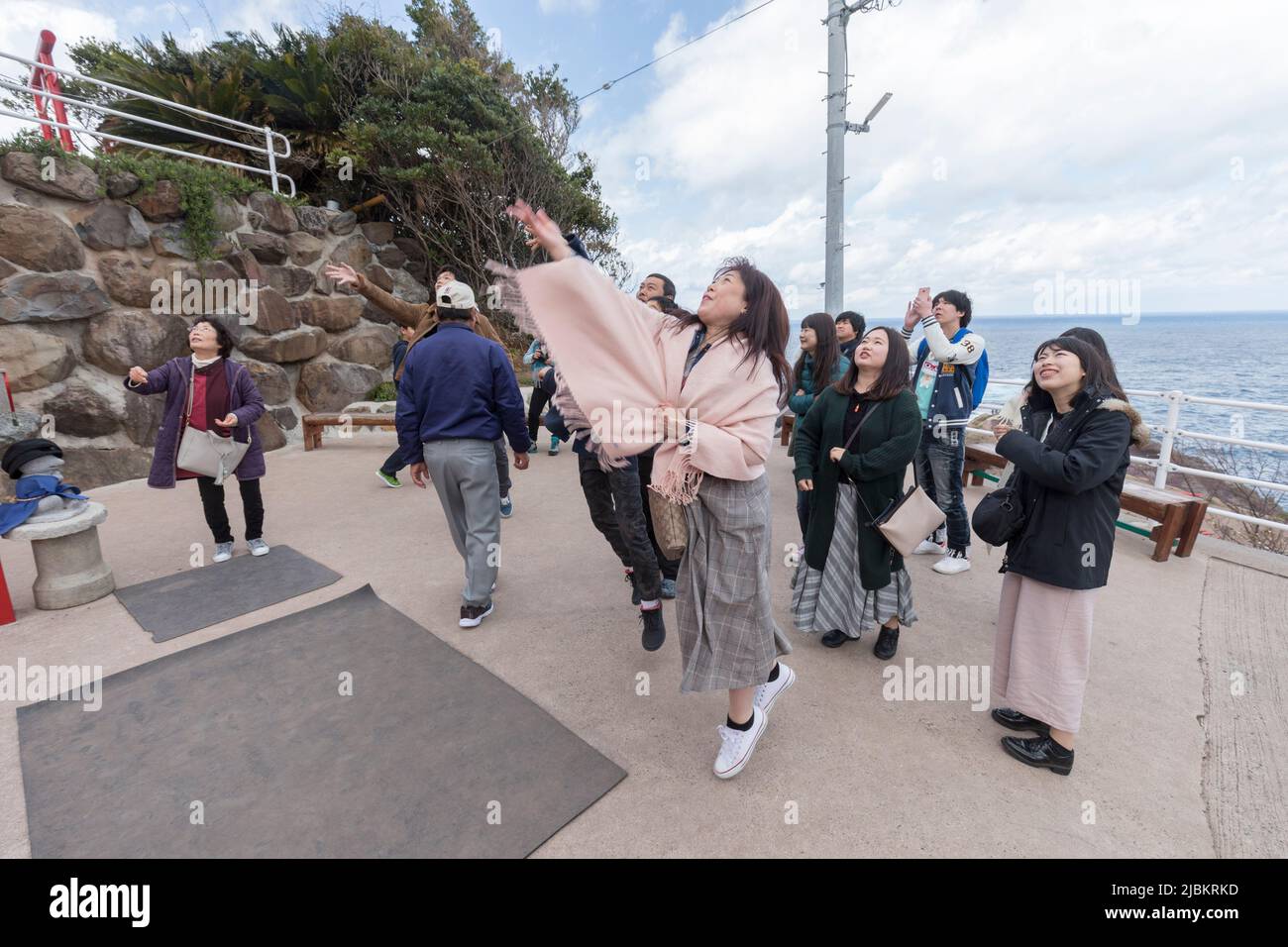 Gente japonesa lanzando piedras a través del arco de la puerta del tori para buena suerte en el santuario de Motonosumi, Nagato, Japón Foto de stock