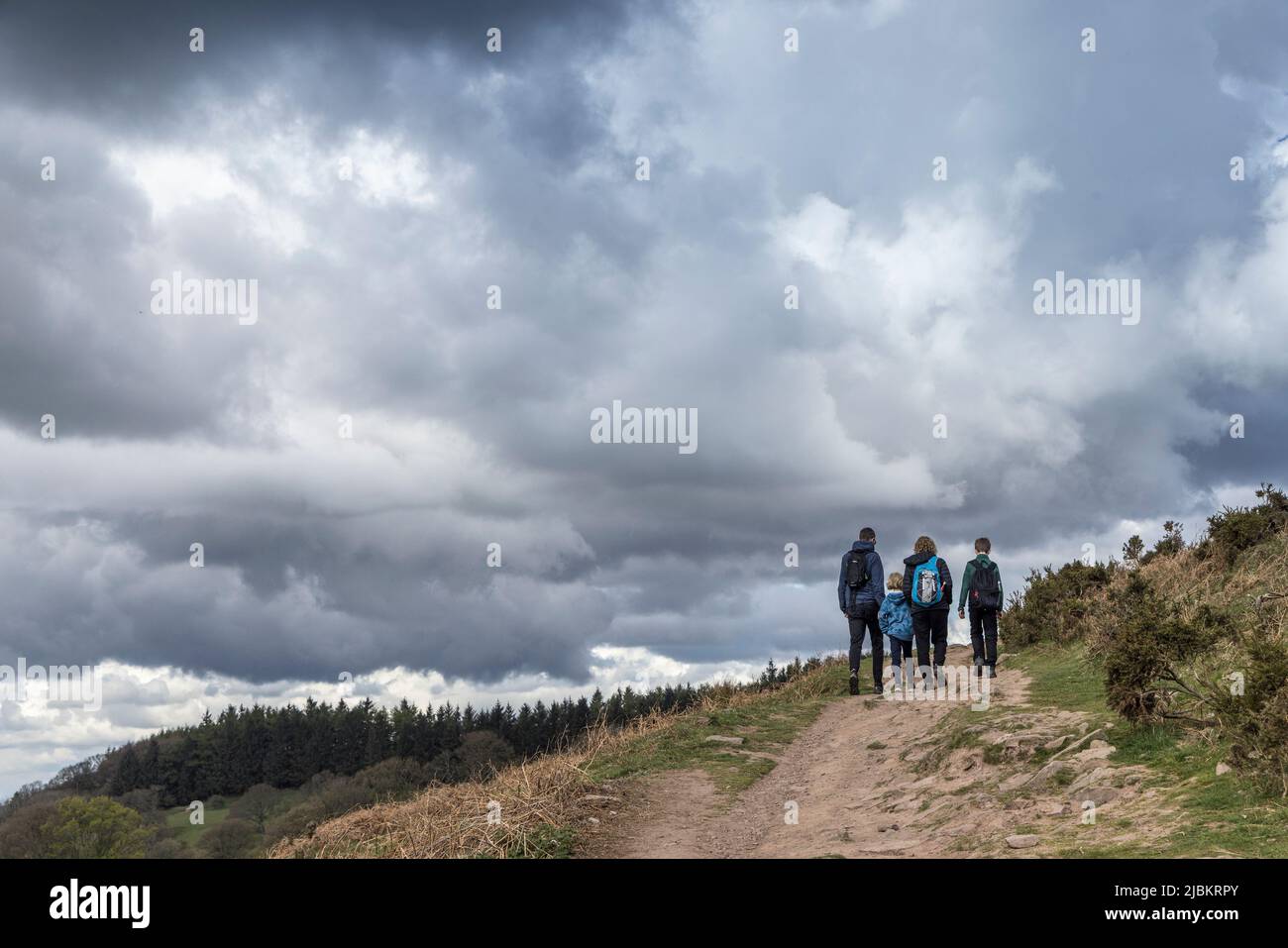 Grupo de dos adultos y niños caminando por la ruta Sugar Loaf en clima nublado, Abergavenny, Gales, Reino Unido Foto de stock
