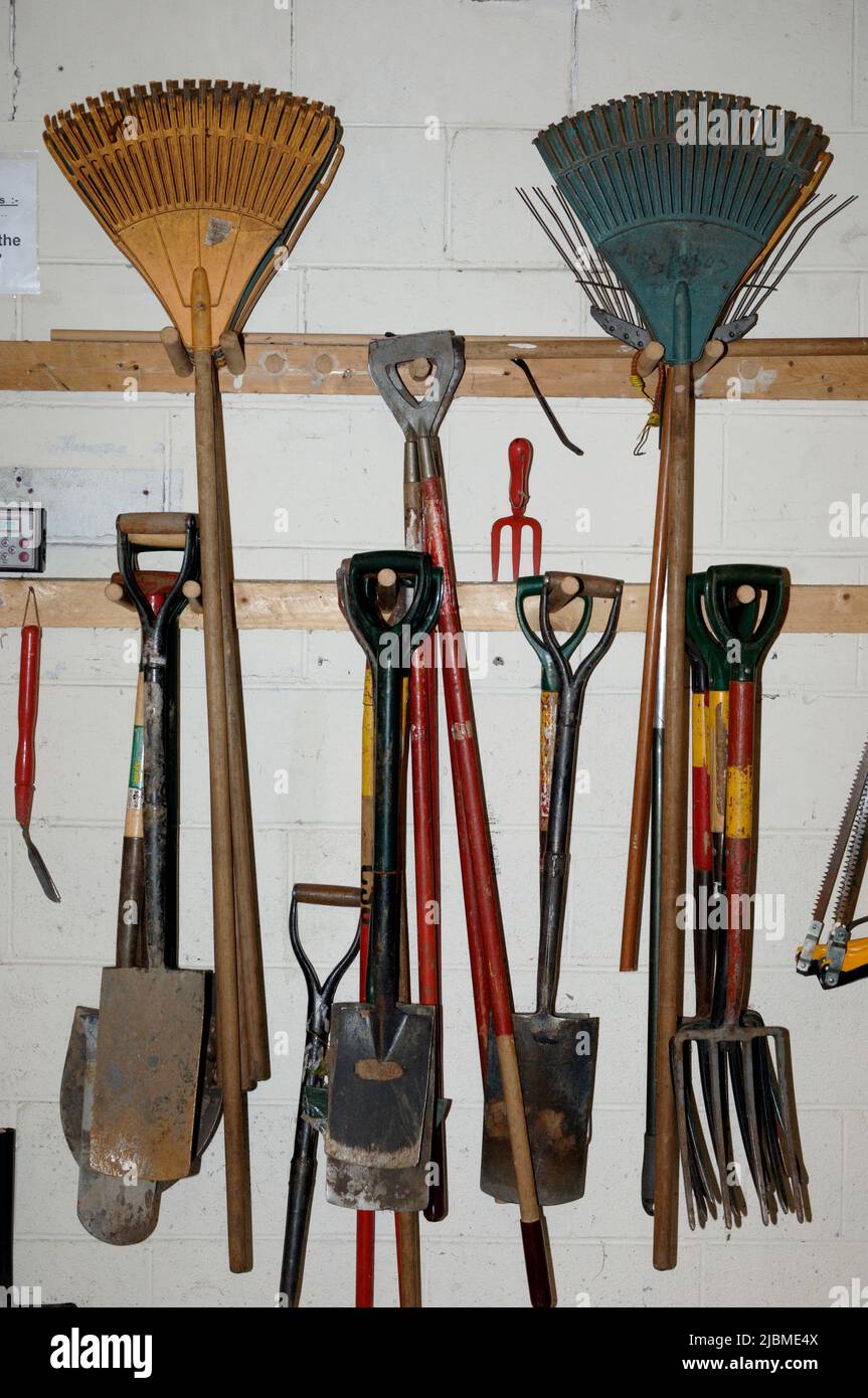 Una colección de herramientas de jardinería colgada en una pared Foto de stock