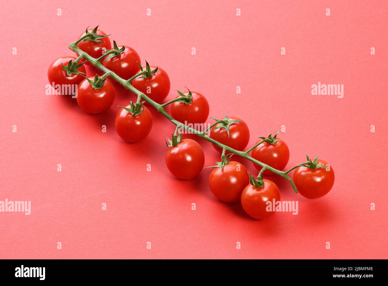 Supermercado tomates de vid sobre fondo rojo Foto de stock