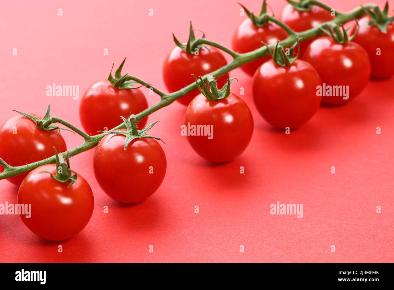 Supermercado tomates de vid sobre fondo rojo Foto de stock