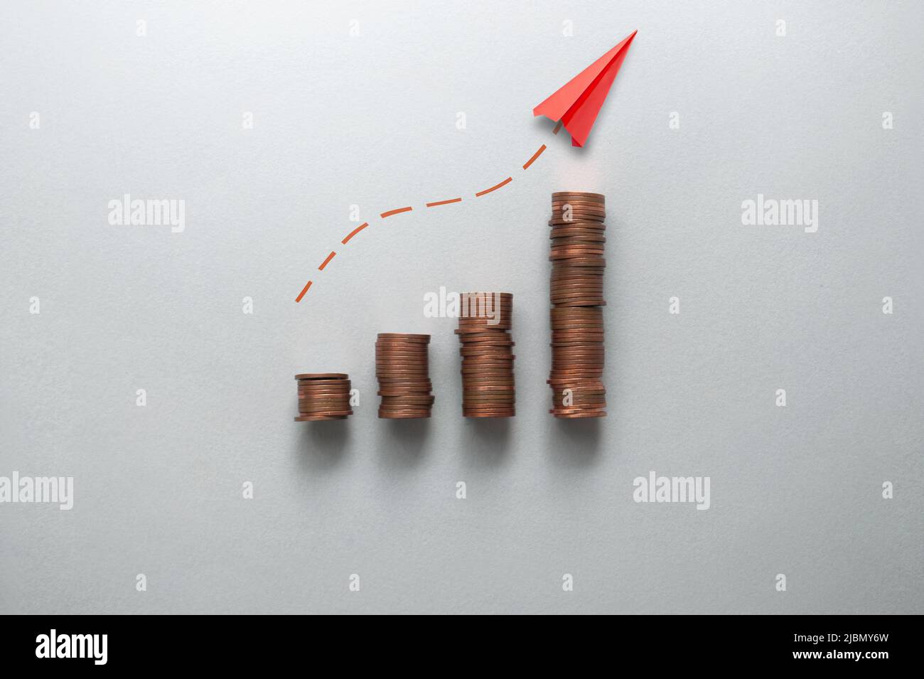Concepto de aumento de la inflación, los costes y los precios, gráfico de negocios pilas de monedas con el papel de avión que se mueve hacia arriba Foto de stock