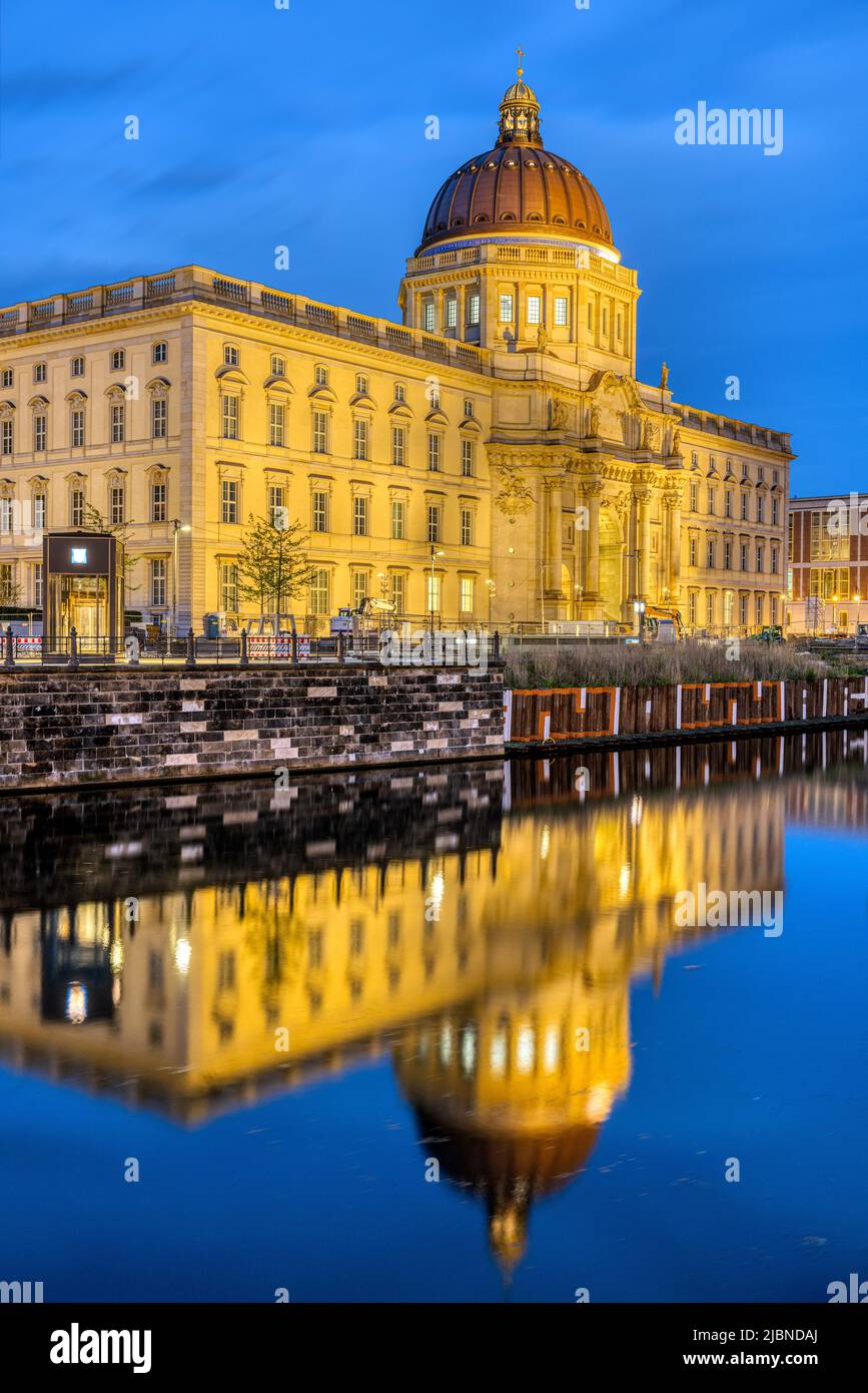 El hermoso Palacio de la Ciudad reconstruido en Berlín por la noche se refleja en un pequeño canal Foto de stock