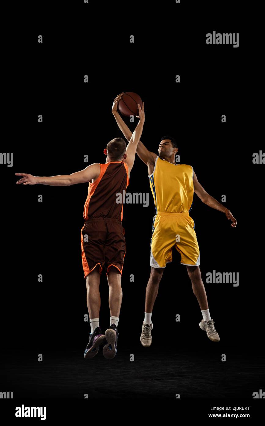 Disparo dinámico de dos jugadores profesionales de baloncesto en  movimiento, en un salto, entrenamiento aislado sobre fondo de estudio  negro. Pase de salto Fotografía de stock - Alamy