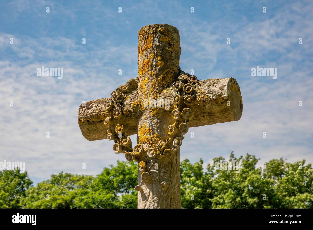 Lápida cruz con guirnalda de flores talladas contra un cielo azul claro, Iglesia de Todos los Santos, Saxstead, Suffolk Foto de stock
