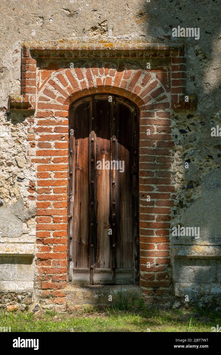 Pequeña puerta de madera con ladrillo rojo y molde de piedra de deriva en forma, All Saints Church, Saxstead, Suffolk Foto de stock