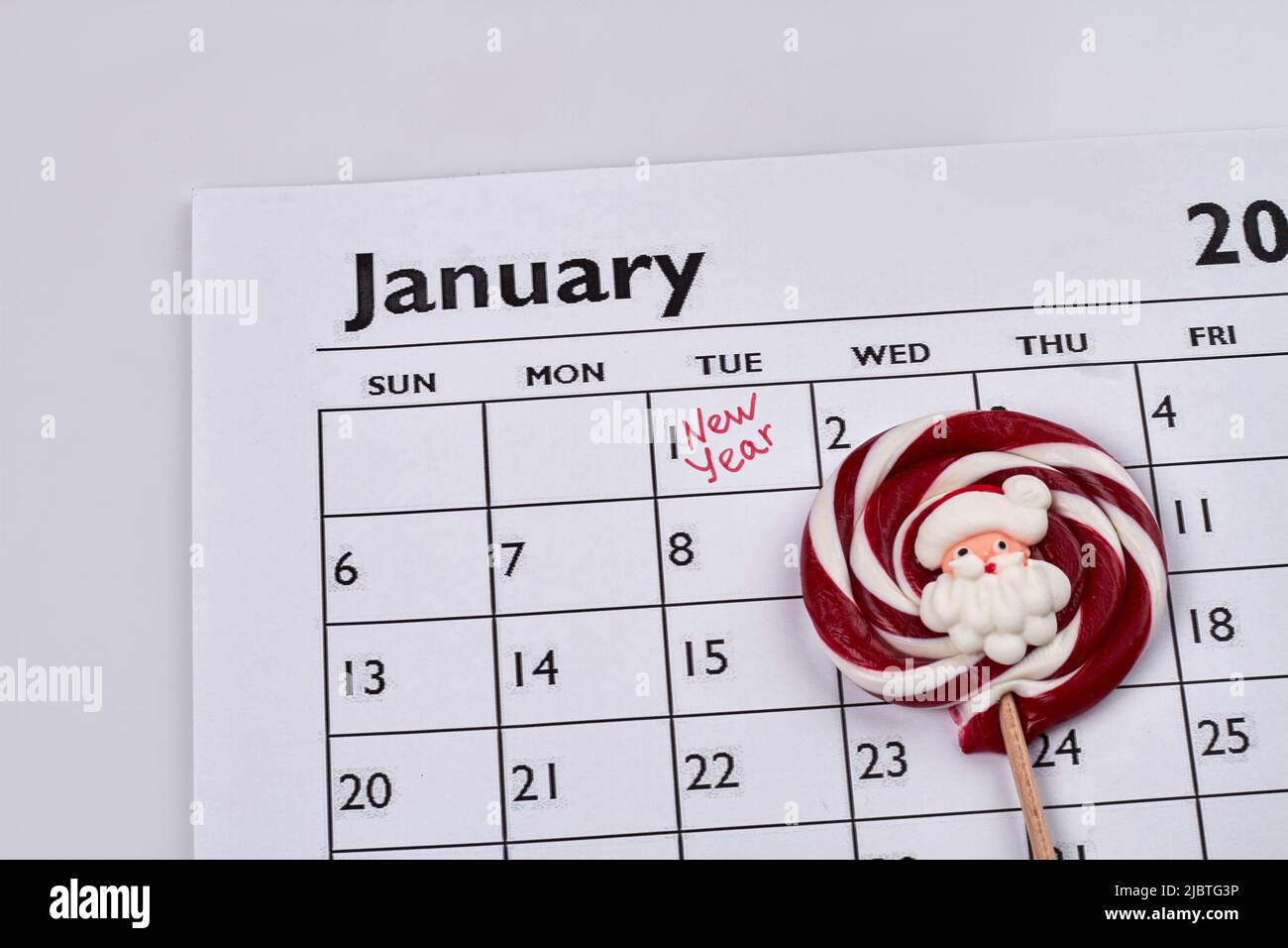Dulce de caramelo redondo con santa en el calendario de enero de papel. Día de Año Nuevo marcado en el calendario. Foto de stock