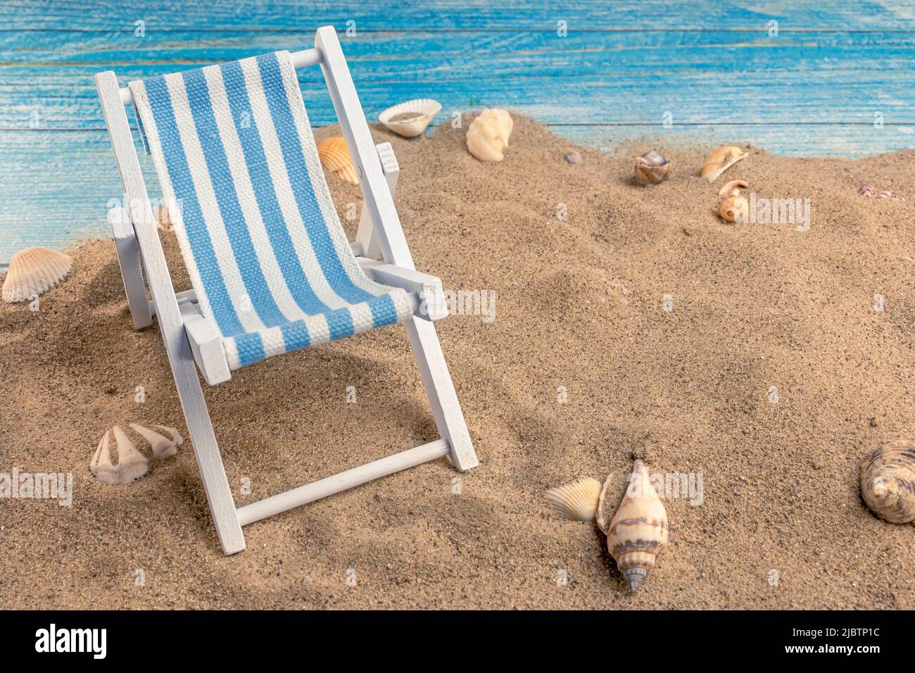 Conchas marinas sobre la arena sobre un fondo azul. Vacaciones de verano, playa, relajación, mar, océano, concepto de viaje. Foto de stock