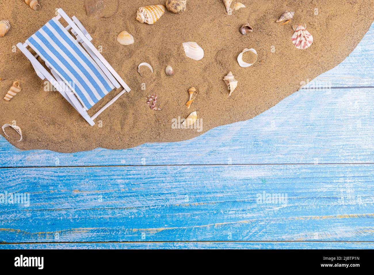 Tumbona y conchas sobre la arena sobre un fondo azul. Vacaciones de verano, playa, relajación, mar, océano, concepto de viaje. Foto de stock