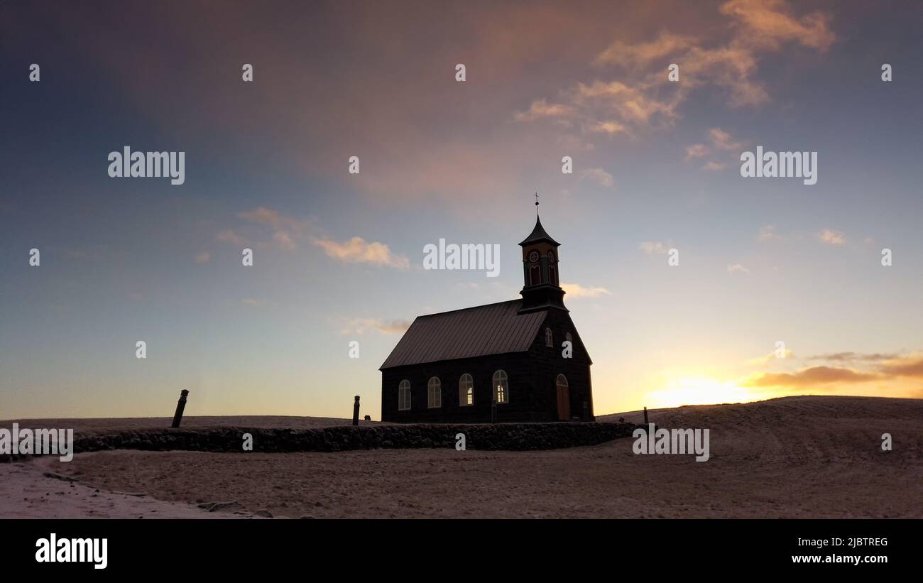 Hvalsneskirkja iglesia situada cerca de la aldea de Sandgerdi en Islandia en invierno al atardecer. Foto de stock