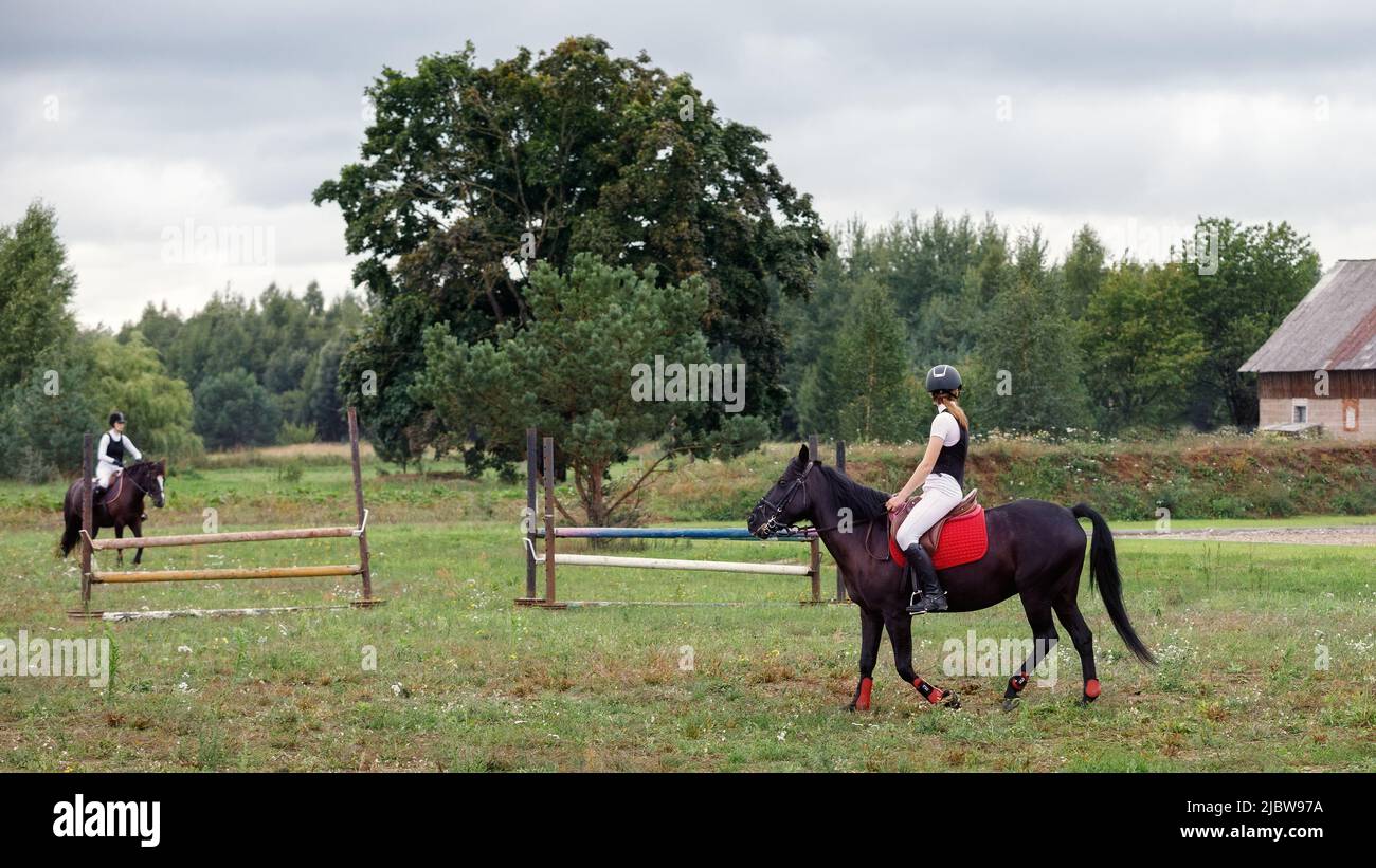 Las chicas jóvenes doman sus caballos antes de la competición en la granja de espárragos. Foto de stock