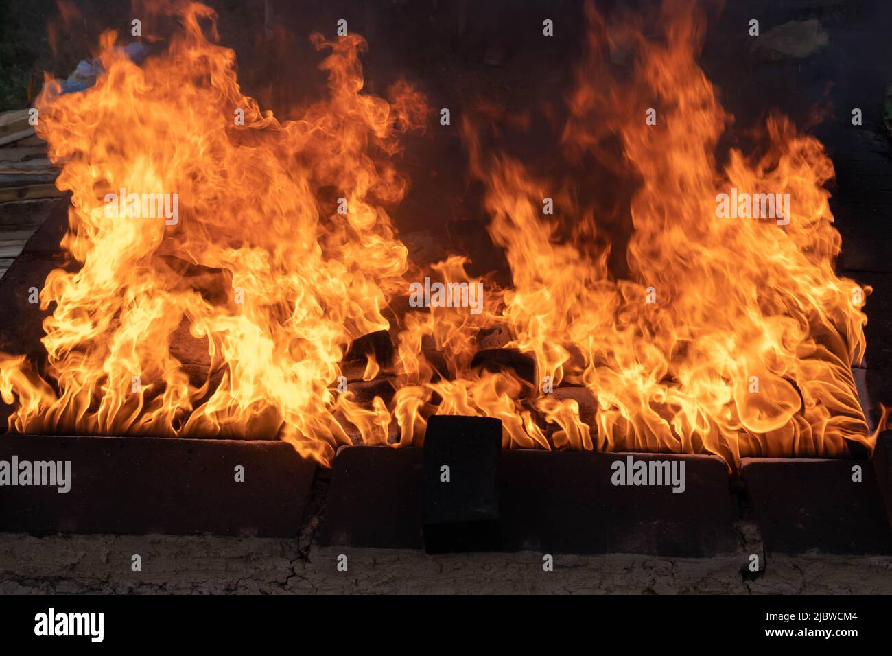 Llamas. El fuego de leña es parte del proceso de cerámica negra. Exclusivas ollas y sartenes hechas a mano hechas de arcilla que se vuelven negras después de asar y oxígeno re Foto de stock