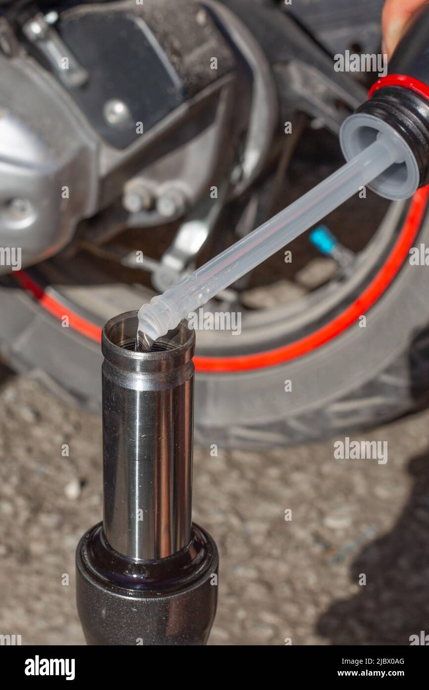 Un mecánico vierte aceite en el amortiguador de la horquilla delantera de  una moto. Cambio de aceite y mantenimiento de motocicletas Fotografía de  stock - Alamy