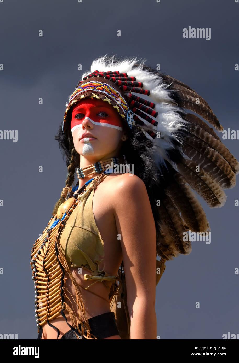 tinta Reorganizar siesta Una mujer india nativa americana se ve parada delante de nubes de tormenta  grises. Lleva un tocado emplumado y tiene ropa tradicional india Fotografía  de stock - Alamy