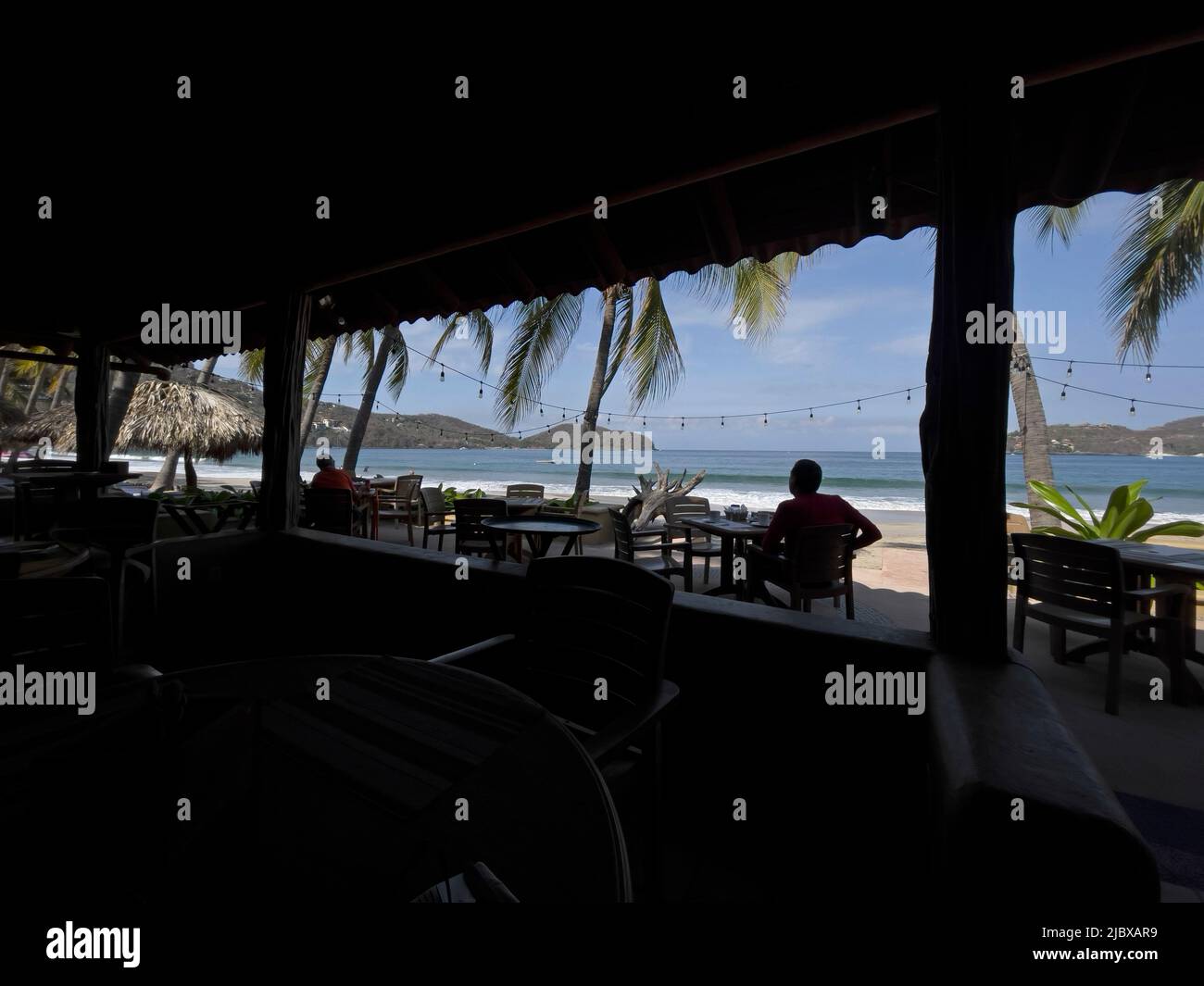 Comer en el restaurante al aire libre en la playa de La Playa Ropa en Zihuatanejo, México Foto de stock